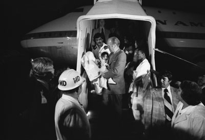 President Ford carries a Vietnamese baby from “Clipper 1742," one of the Operation Babylift planes that transported approximately 325 South Vietnamese orphans from Saigon to the United States. 