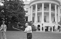 President Ford practices golf on the South Lawn of the White House under the watchful eye of the Secret Service.  May 9, 1975.  