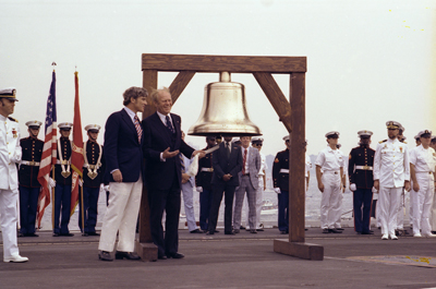 President Ford initiates the ringing of Bicentennial bells across the nation while on the flight deck of the USS Forrestal with Bicentennial Administration head John Warner in observance of Operation Sail activities in New York Harbor. 