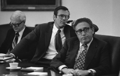 Philip Buchen, Counsel to the President, Chief of Staff Donald H. Rumsfeld and Secretary of State Henry A. Kissinger attend to a map presentation by Acting Chairman of the Joint Chiefs of Staff David C. Jones (USAF) on the status of the rescue operation to gain the release of the crew of the S.S. Mayaguez. 