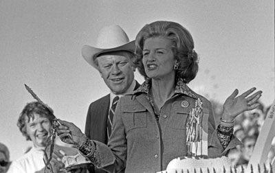President Ford stands by as First Lady Betty Ford prepares to cut the birthday cake at the dedication ceremony for the Oklahoma State Fair Grounds’ Independence Arch and Constitution Fountain.  Oklahoma City, Oklahoma.  September 19, 1975