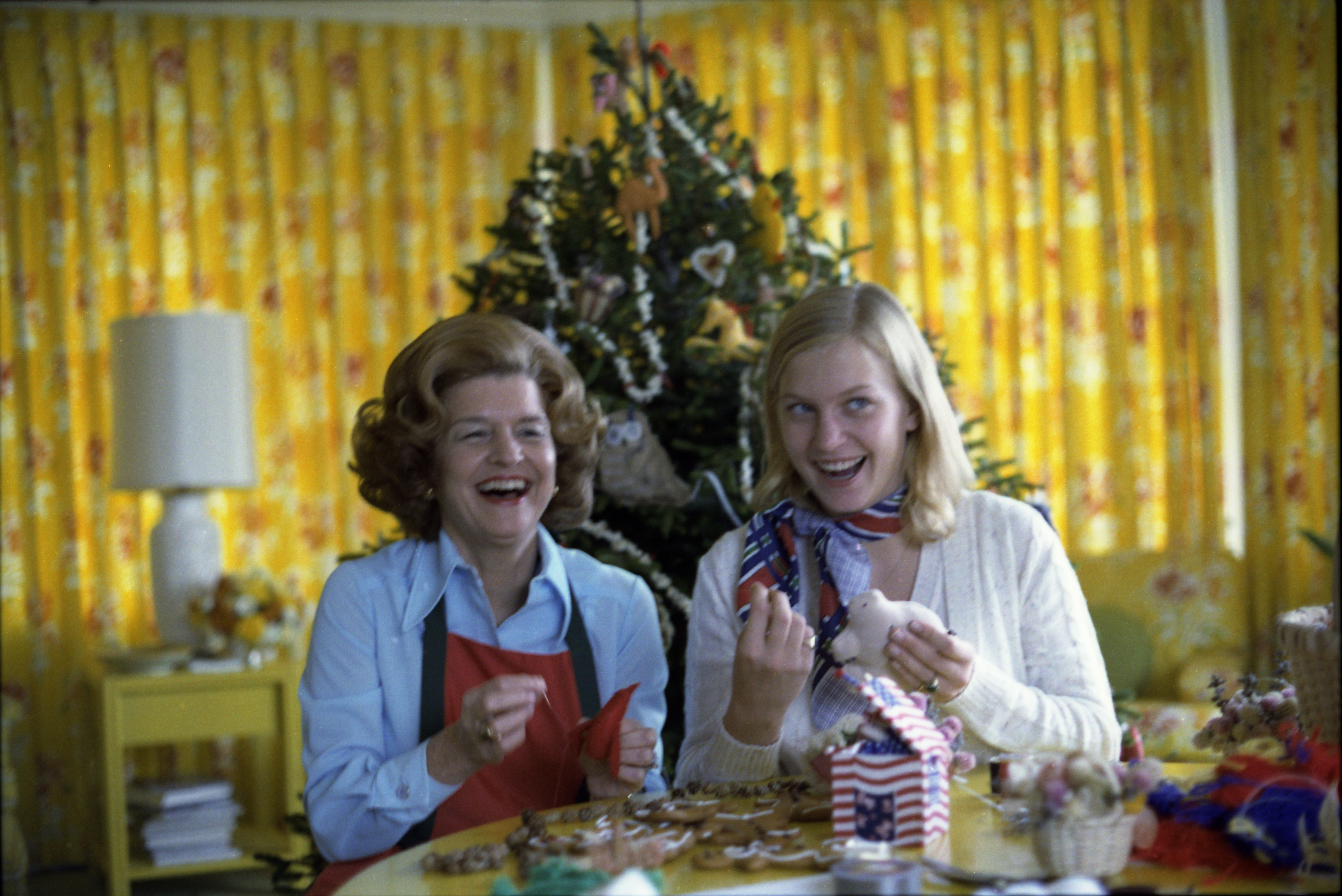 Having selected “handmade and folksy” as the theme for Christmas at the White House, First Lady Betty Ford makes homemade ornaments with daughter Susan for the tree in the third floor Solarium during a photo-op for Parade Magazine.  