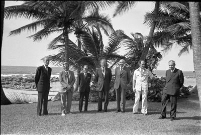 The participants in the Second International Economic Summit Conference gather under the palms for a press photo. 