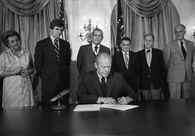 President Ford signs S.3735, authorizing the 1976 National Swine Flu Immunization Program.  August 12, 1976.  Also shown are [l-r]:  HEW Undersecretary Marjorie Lynch, HEW Secretary F. David Mathews, U.S. Rep. Tim Lee Carter (R-KY),  Assistant Secretary for Health (HEW) Dr. Theodore Cooper, HEW General Counsel William H. Taft, IV, and HEW Assistant General Counsel Bernard Feiner.