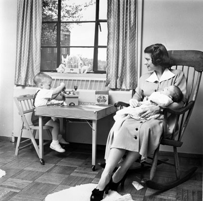 Betty Ford holds her second son, Jack, while her eldest son Michael plays at a small table in their apartment at 1521 Mount Eagle Place, Alexandria, Virginia. 