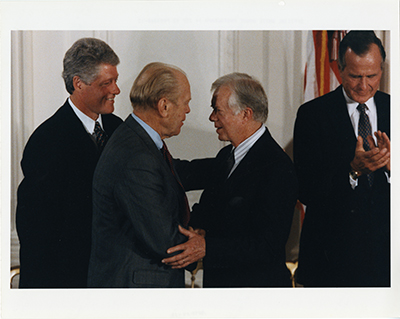 Former Presidents Gerald R. Ford and Jimmy Carter embracing during the ceremony for the signing of the North American Free Trade Agreement (NAFTA).