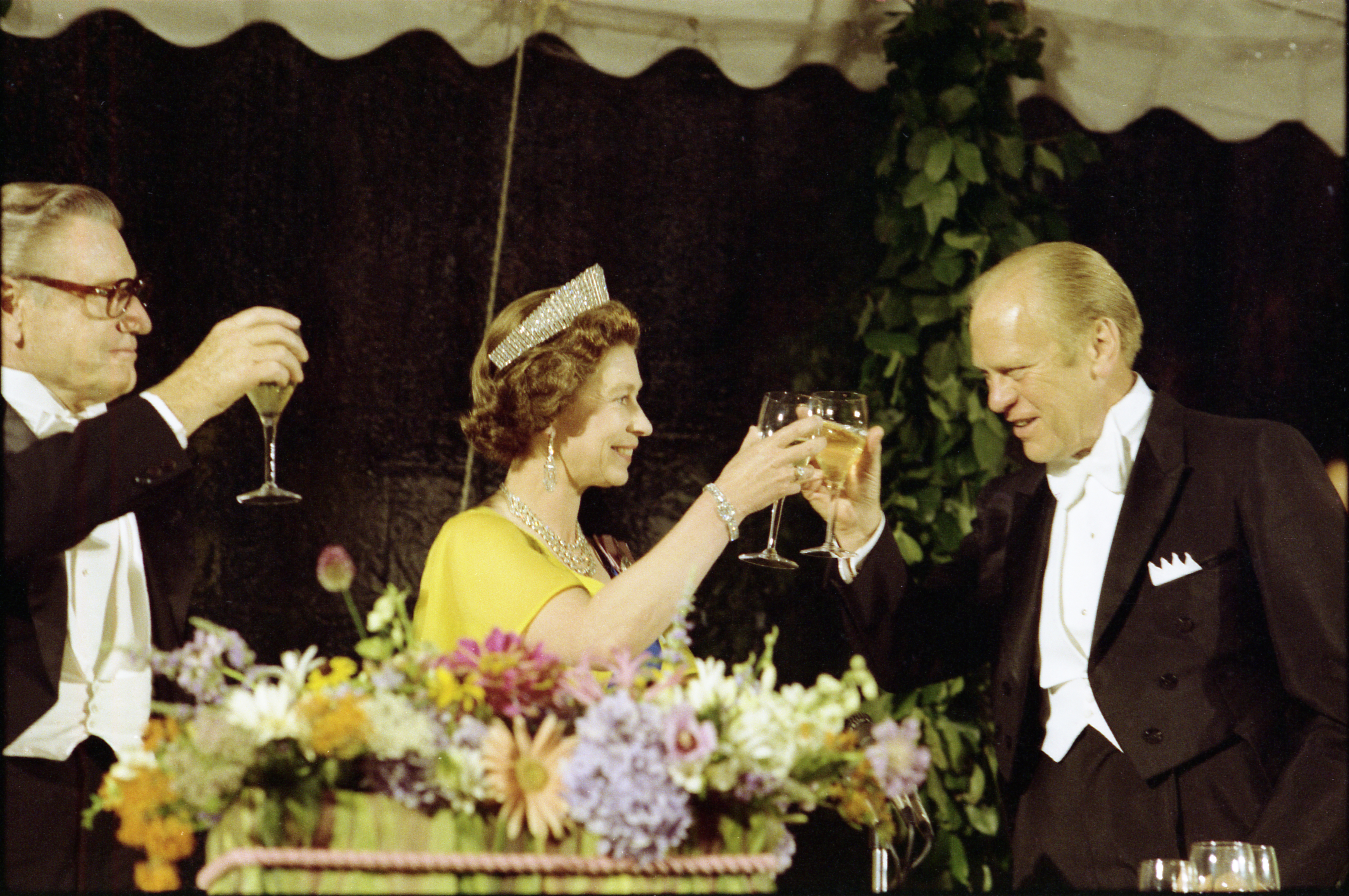 President Ford, Vice President Nelson Rockefeller, and Queen Elizabeth II raising their glasses in a toast at a state dinner honoring Her Majesty.