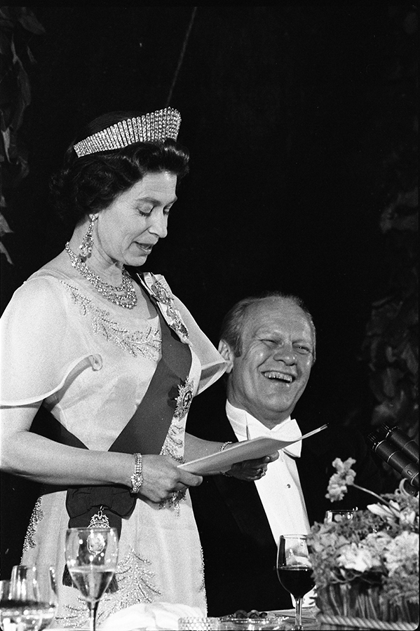 President Ford laughing as Queen Elizabeth II delivers remarks at a state dinner honoring Her Majesty.