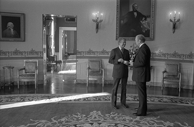 President-elect Jimmy Carter and President Ford talking during a reception for the Carters and the Mondales in the Blue Room at the White House prior to the inauguration ceremony.