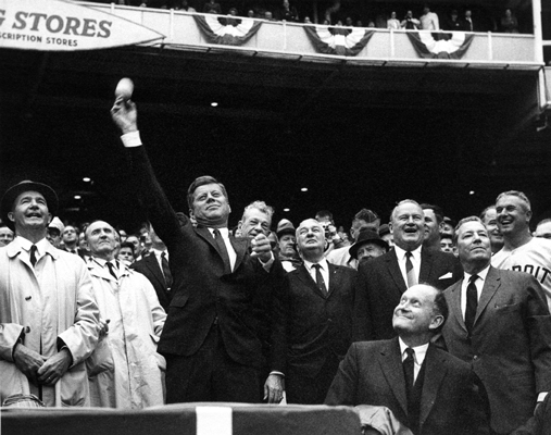 President John F. Kennedy tosses out the first pitch in Washington’s 1962 home opener as American League President Joe Cronin, Senators President Elwood Quesada, and Detroit Tigers Manager Bob Scheffing look on.