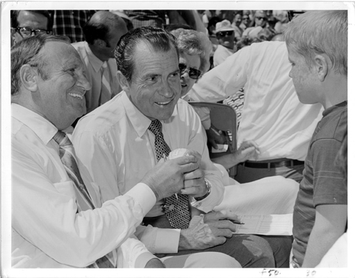 Richard Nixon and Los Angeles Angels owner Gene Autry greet a young fan in the stands at a game. 