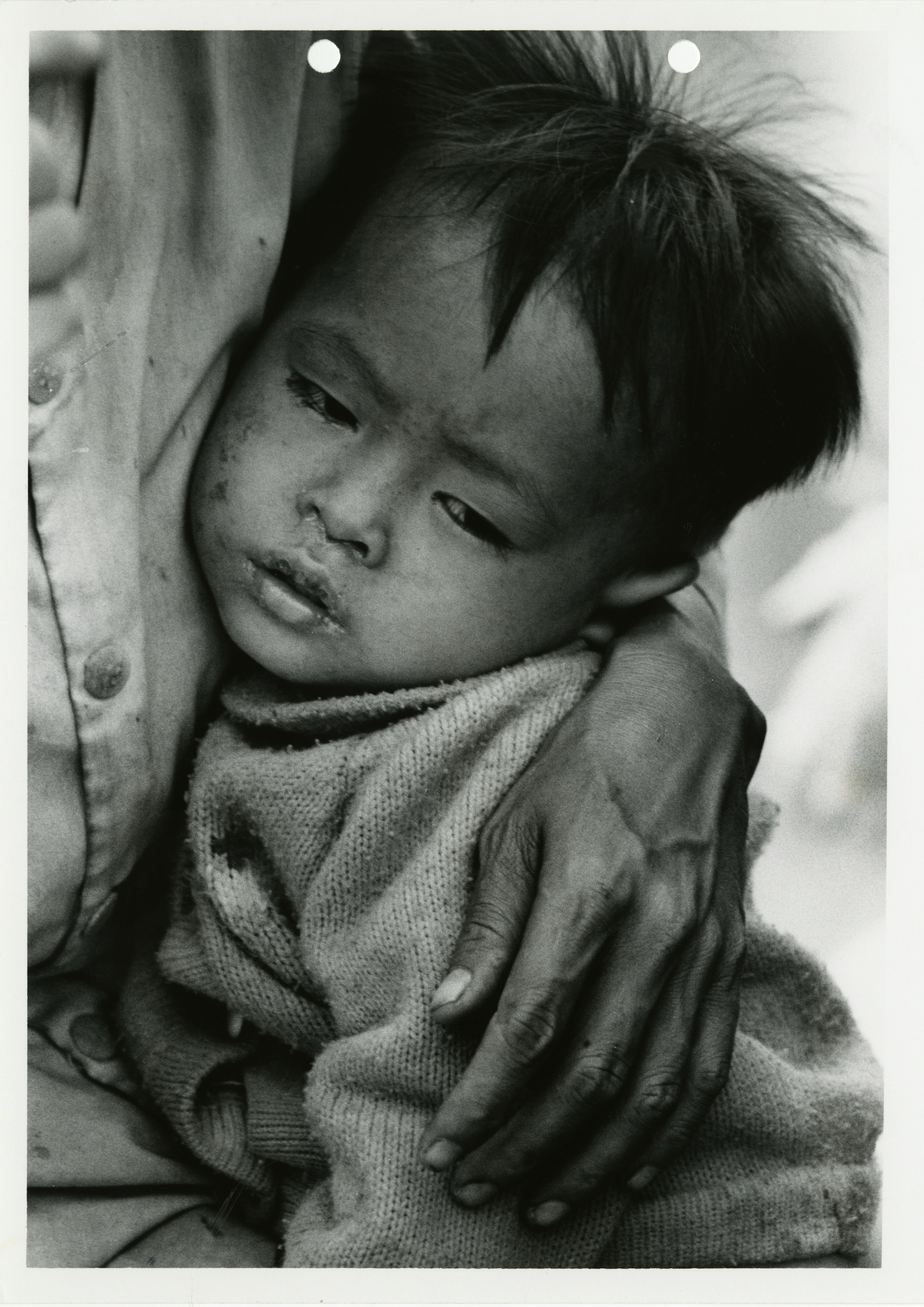 A sick Vietnamese child is comforted in its mother’s arms at Cam Rahn Bay, South Vietnam. March 29 or 30, 1975. 