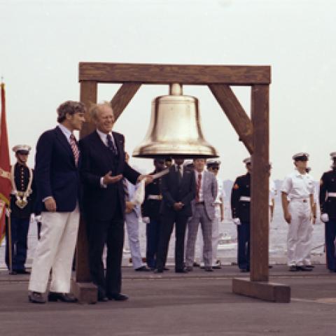 B0493-15 - President Ford initiates the ringing of Bicentennial bells across the nation while on the flight deck of the USS Forrestal with Bicentennial Administration head John Warner in observance of Operation Sail activities in New York Harbor. July 4, 1976.