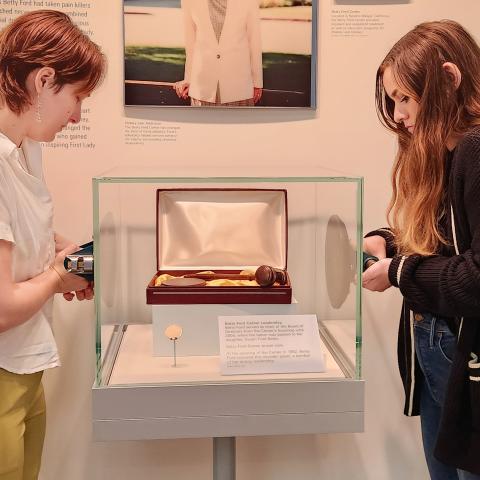 Two interns are preparing to adjust an artifact in a glass case