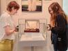 Two interns are preparing to adjust an artifact in a glass case
