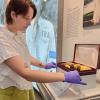 Intern with gloves on, is adjusting a gavel artifact