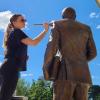 An intern on a ladder cleans a statue