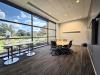 A conference room with a large oval table and two smaller high top tables is shon