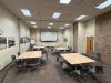 Tables in an empty classroom are set up in pod formation with chairs