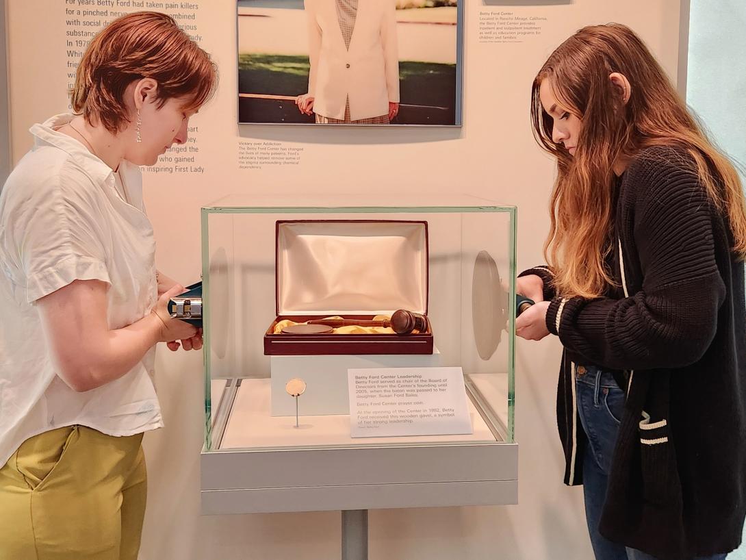Two interns are preparing to adjust an artifact in a glass case