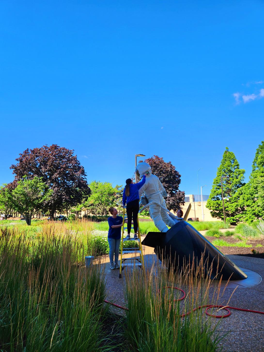 Two interns are washing a statue outside