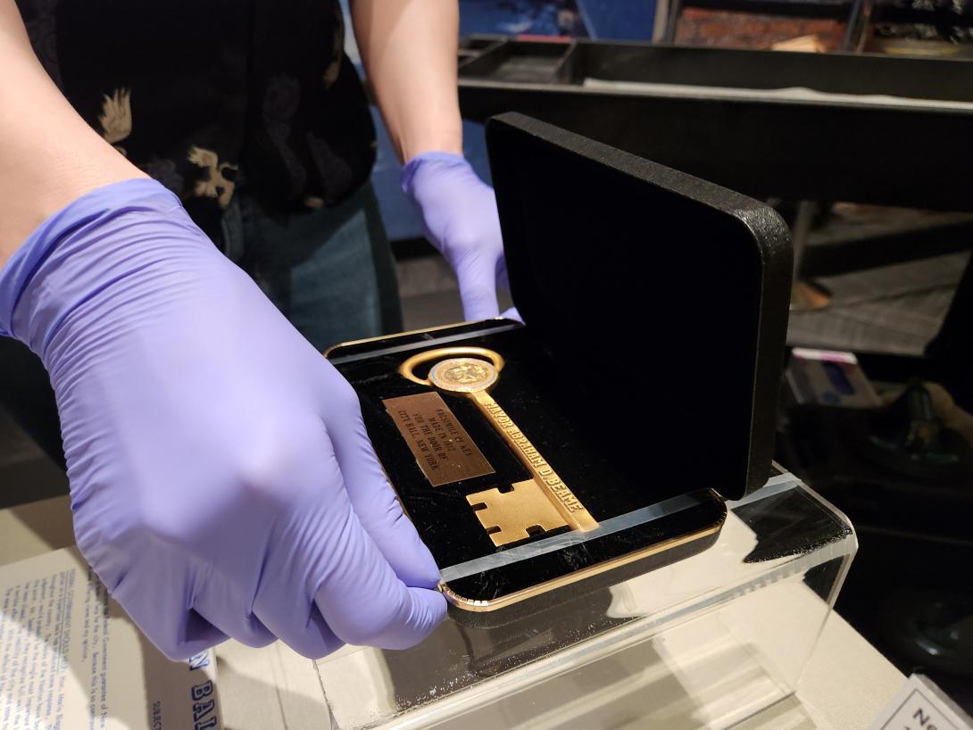 Intern with gloves on is adjusting a key artifact