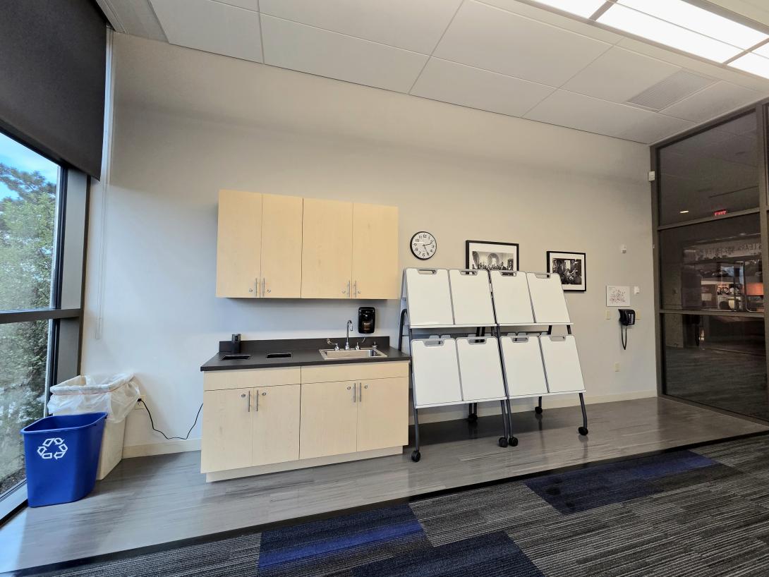 A sink, cabinets and whiteboards are shown in a small classroom