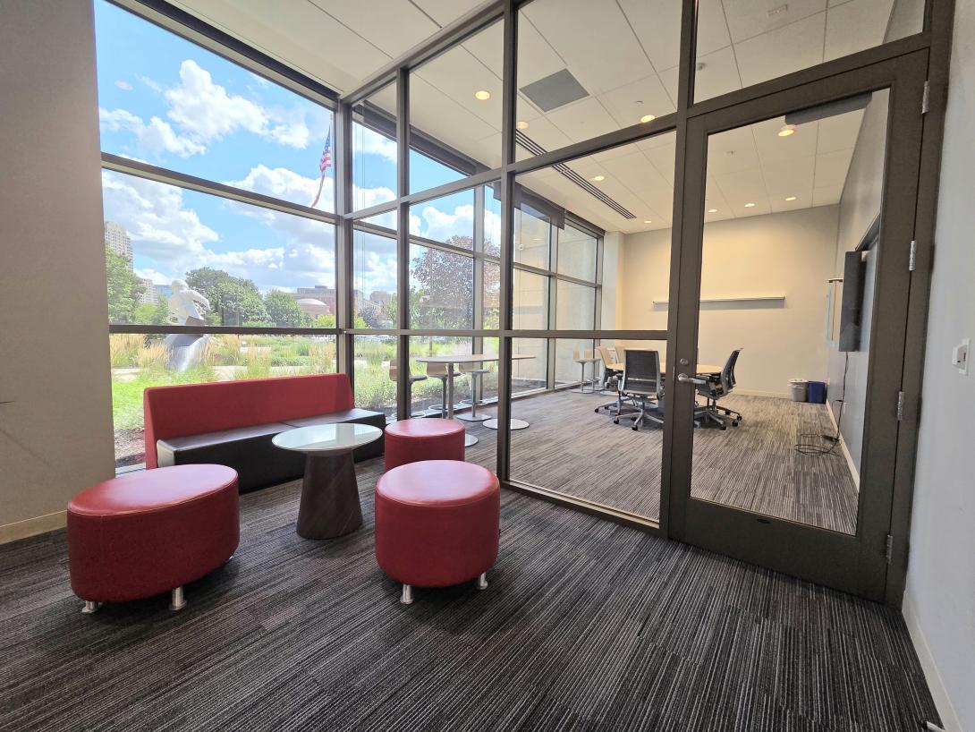 Red stools and a bench are shown outside of a conference room door