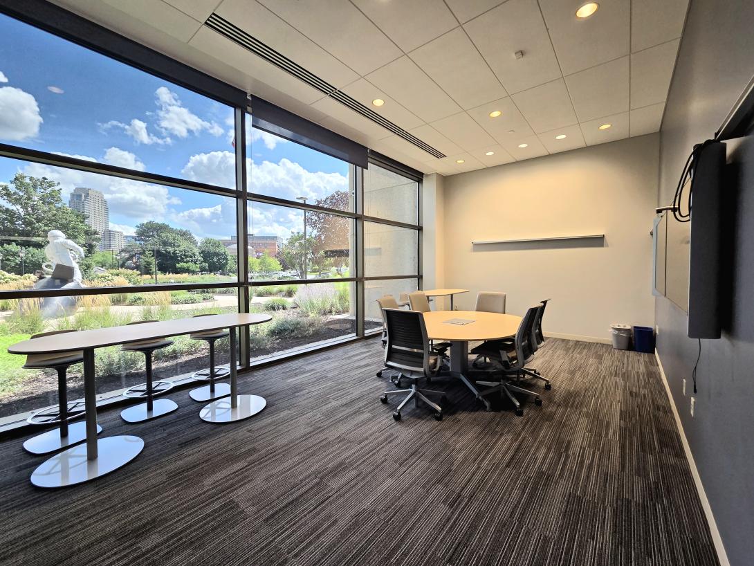 A conference room with a large oval table and two smaller high top tables is shon