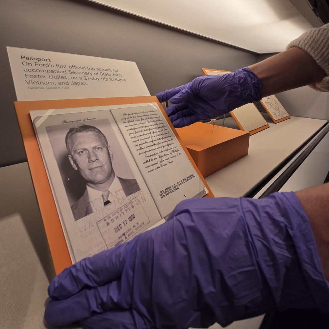 An intern with gloves adjusts an artifact in a case