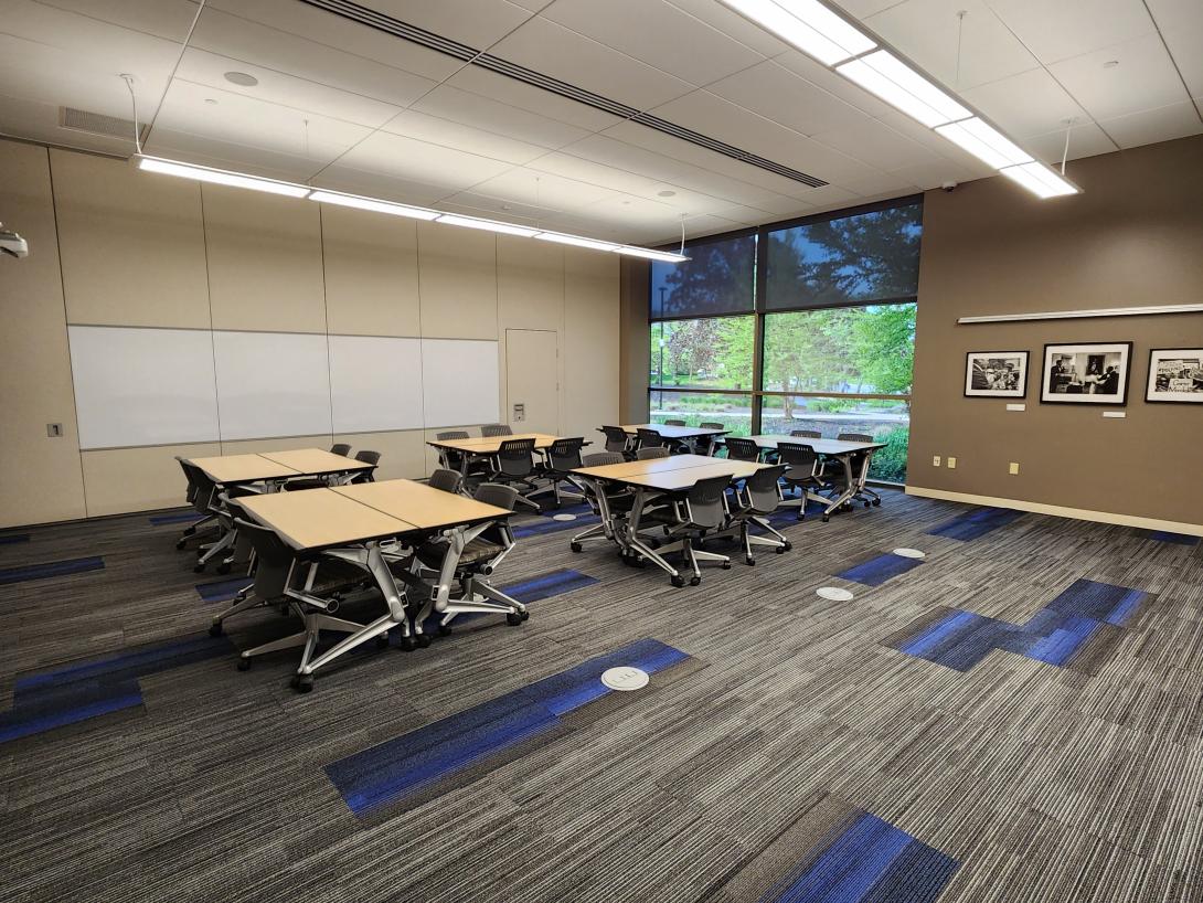 A room with an extended wall divider, tables and chairs are shown