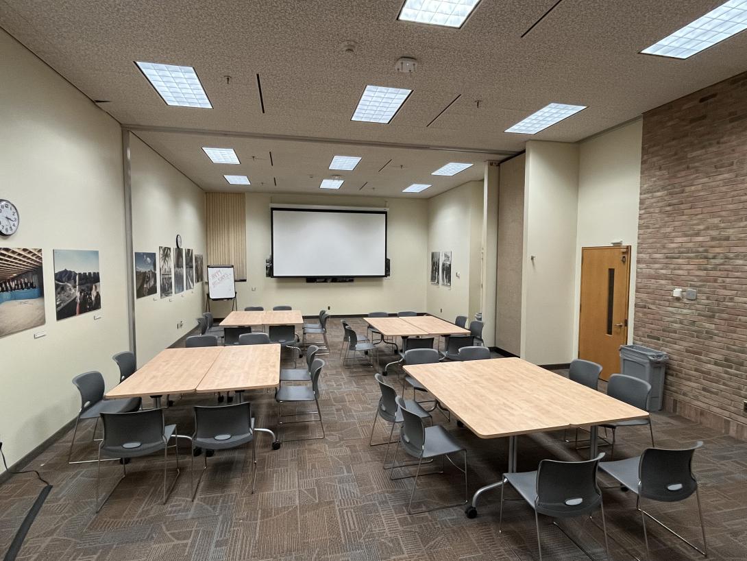 Tables in an empty classroom are set up in pod formation with chairs