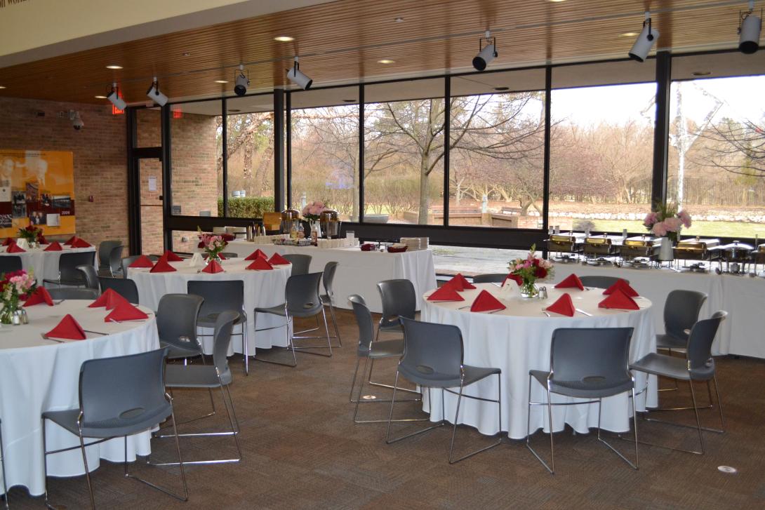Round tables with white tablecloths are set up for an event in the lobby